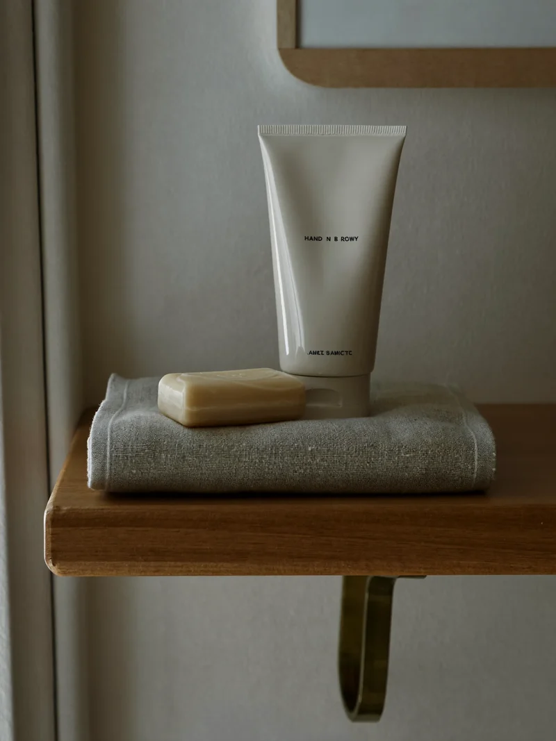 Tube de crème, pain de savon et linge plié sur une étagère en bois